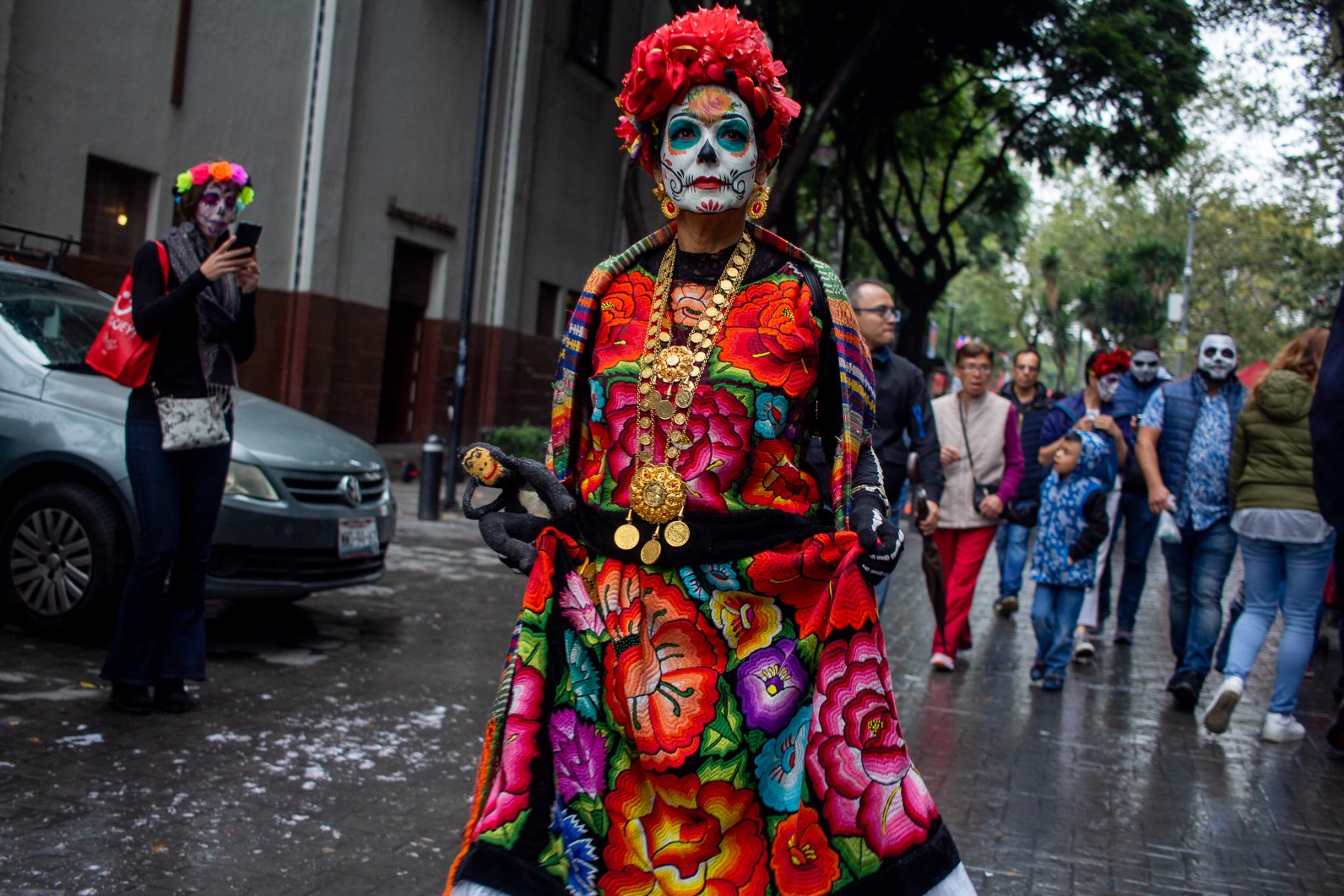 A woman with traditional <em>catrina</em> face paint leaves the parade. Elegantly dressed people made up like so is the enduring image of Dia de Muertos, and face painters roam throughout the streets offering their services.