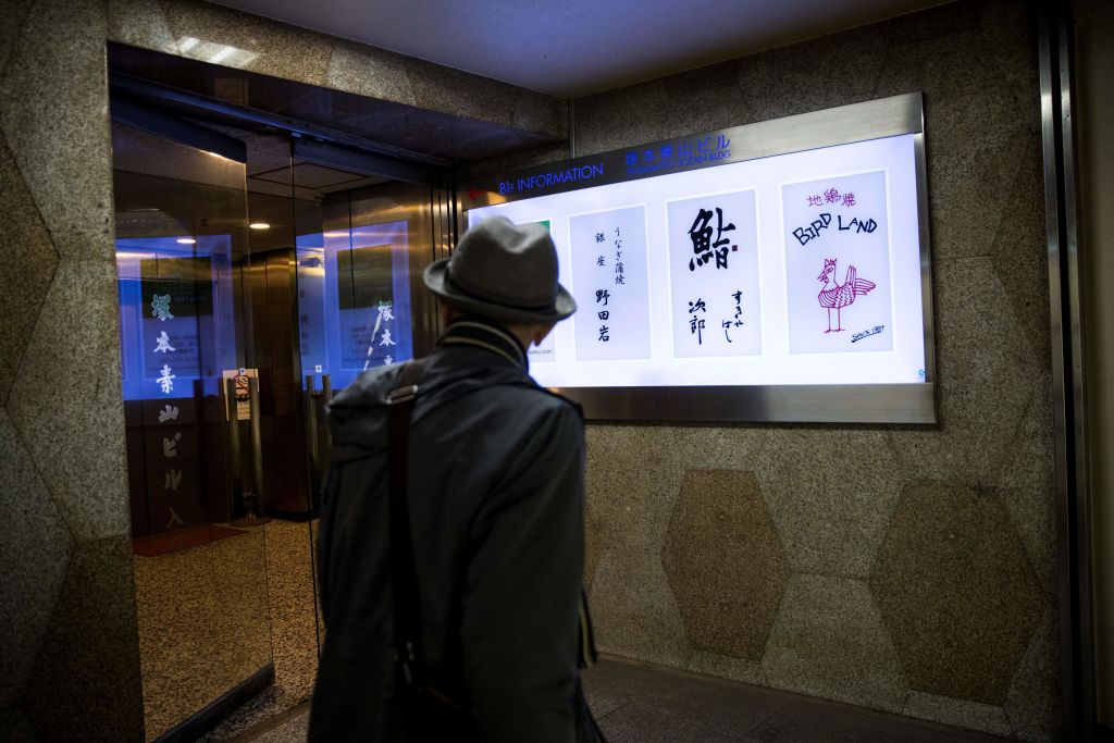 A man walks past the board of Sukiyabashi Jiro sushi restaurant (2nd R) in Tokyo on November 26, 2019. - The famed Tokyo sushi restaurant where Barack Obama is said to have enjoyed the best sushi of his life has been dropped from the latest Michelin gourmet guide after it stopped accepting reservations from the general public. (Photo by Behrouz MEHRI / AFP) (Photo by BEHROUZ MEHRI/AFP via Getty Images)
