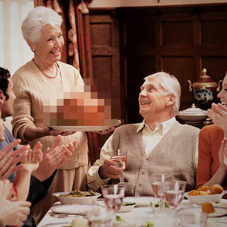 Family sitting down for Thanksgiving dinner, turkey is blurred out
