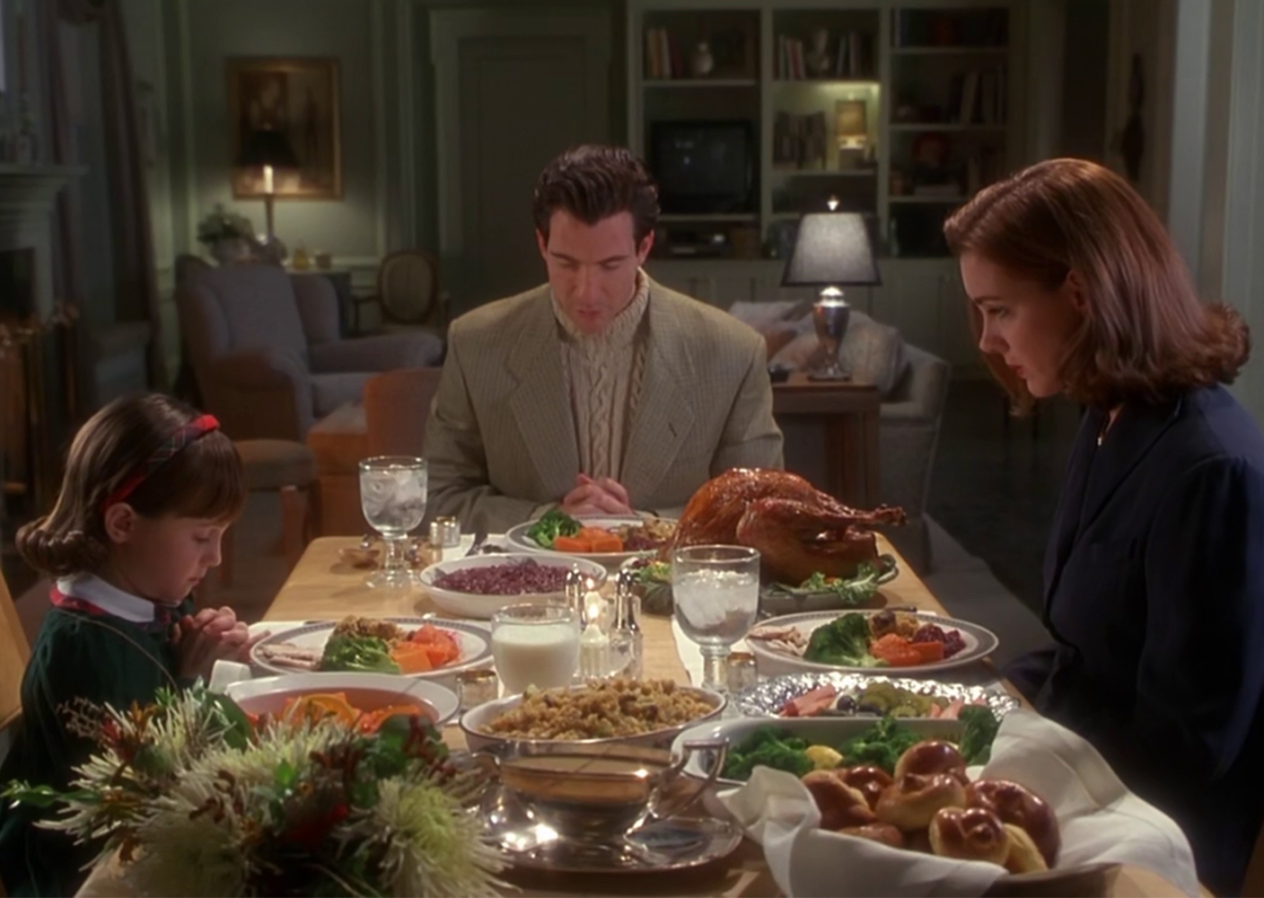 Mara Wilson, Dylan McDermott and Elizabeth Perkins sitting down for Thanksgiving dinner in the 1994 movie Miracle on 34th Street
