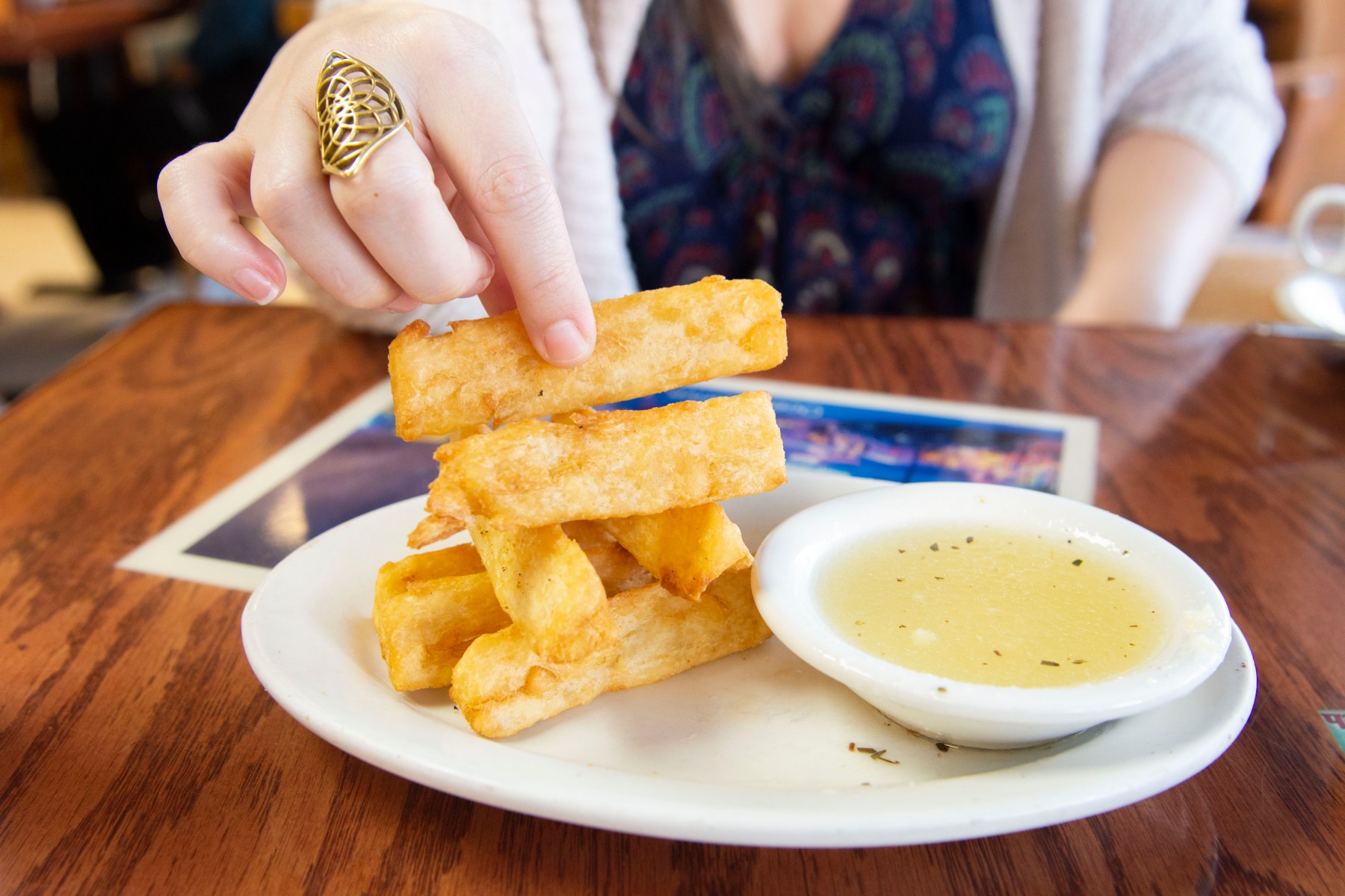Before our food comes, we’re given little white paper bags filled with silver utensils. We start the meal with<br>yuca fries, which come in a neat little stack and a delectable lemon-garlic dipping sauce. The yuca<br>crunches on its own, a soft, buttery tang added by the sauce.