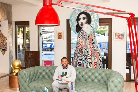 Grutman in his living room, adorned with a Hush sculpture, a Nicolas Party painting, leather couches, and a giant Baxter lamp.