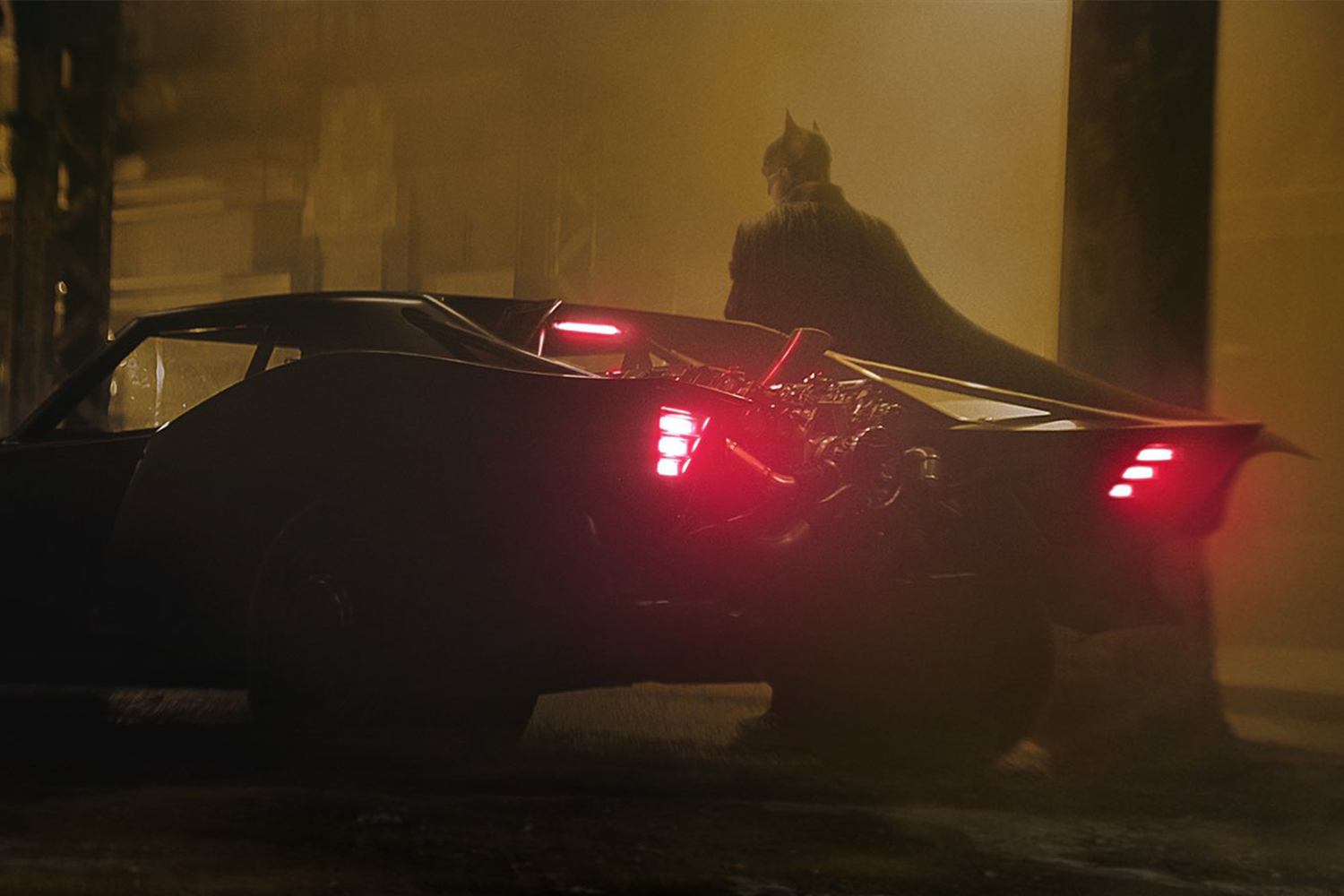 Batman debout à côté de la nouvelle Batmobile
