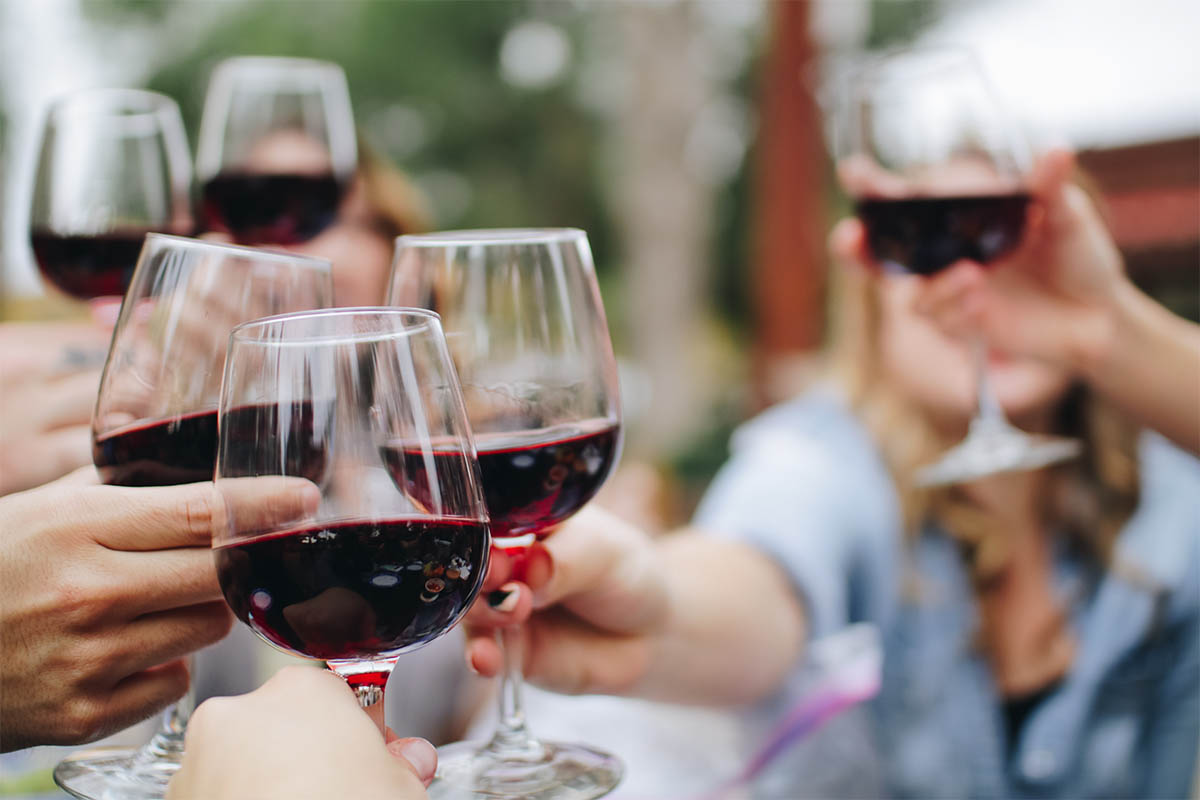 Group of drinkers holding up glasses of red wine