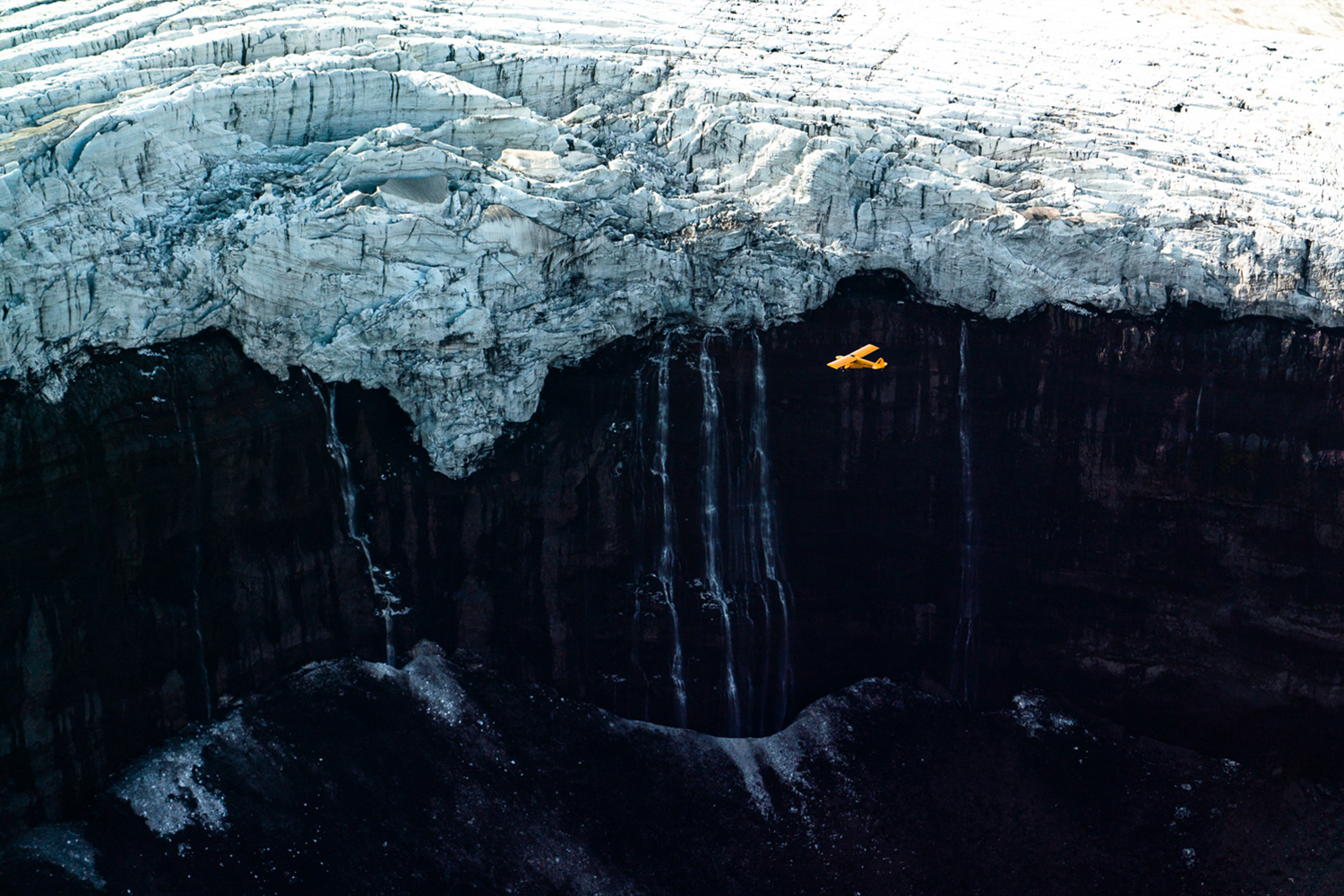 A yellow Cessna flys by Icelandic glaciers