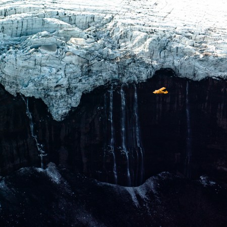 A yellow Cessna flys by Icelandic glaciers