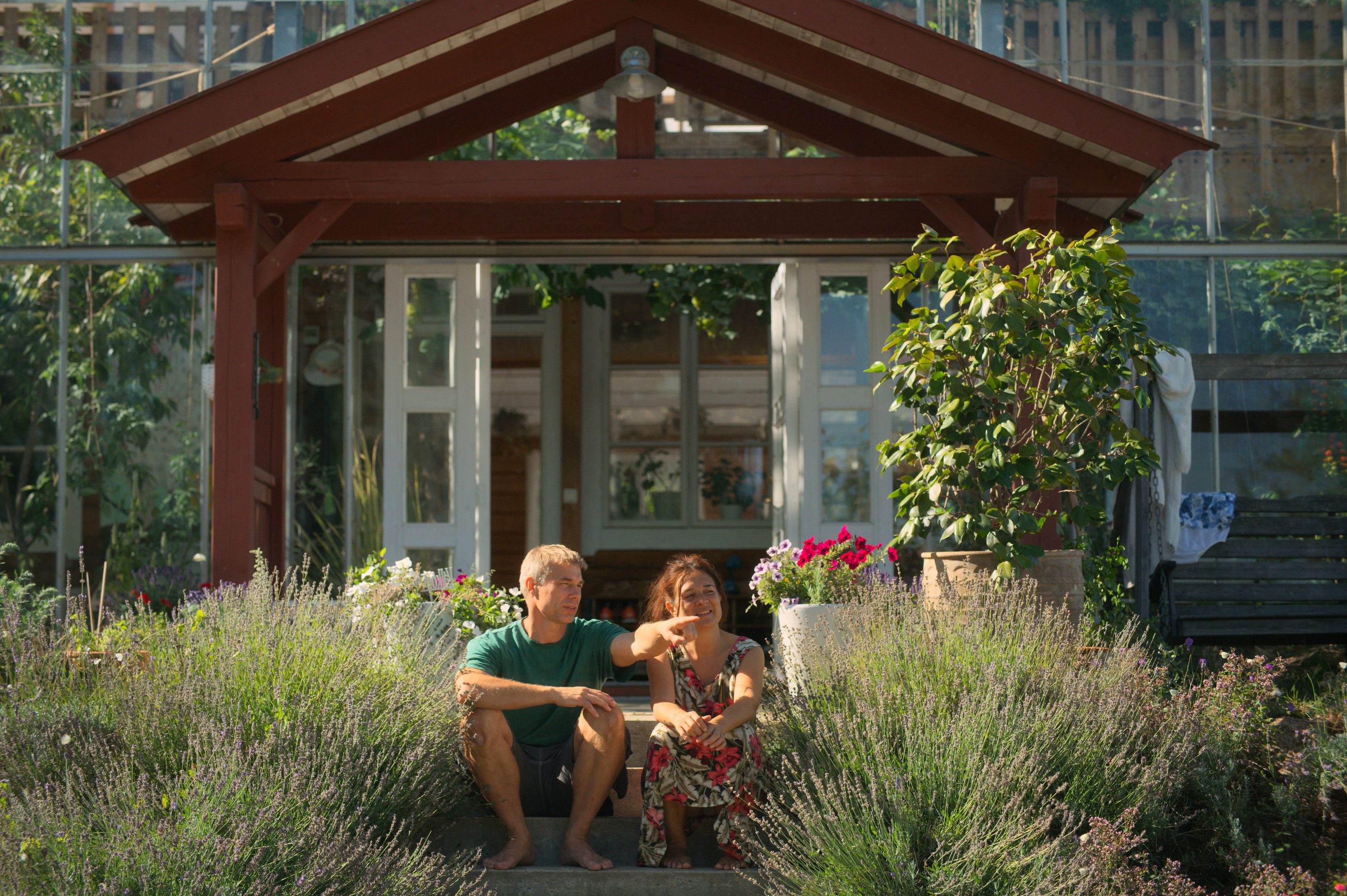 Homeowner Anders Solvarm and his wife in front of their greenhouse home in Sweden. (Courtesy of Apple)