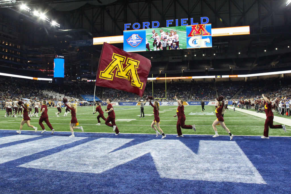 Minnesota cheerleaders run with the school logo flag across the end zone after a score during the Quick Lane Bowl game between the Minnesota Golden Gophers and the Georgia Tech Yellow Jackets on December 26, 2018 at Ford Field in Detroit, Michigan.  Minnesota defeated Georgia Tech 34-10.  (Photo by Scott W. Grau/Icon Sportswire via Getty Images)