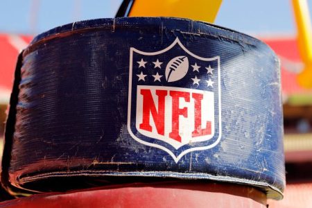The NFL logo on a goal post stanchion. Unvaccinated players in the NFL and their teams are subject to discipline if a positive Covid-19 test occurs.