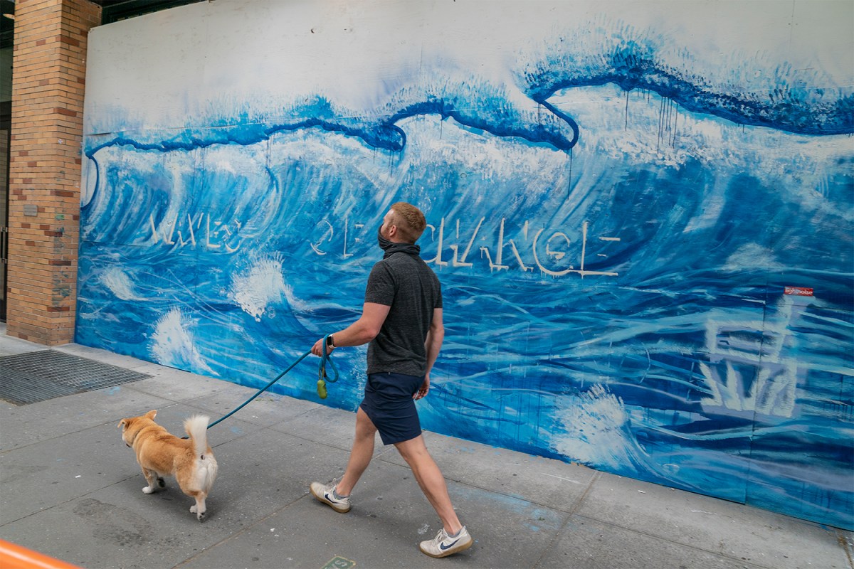 A mural reads "Waves of Change" on the plywood of Moschino in SoHo, NYC