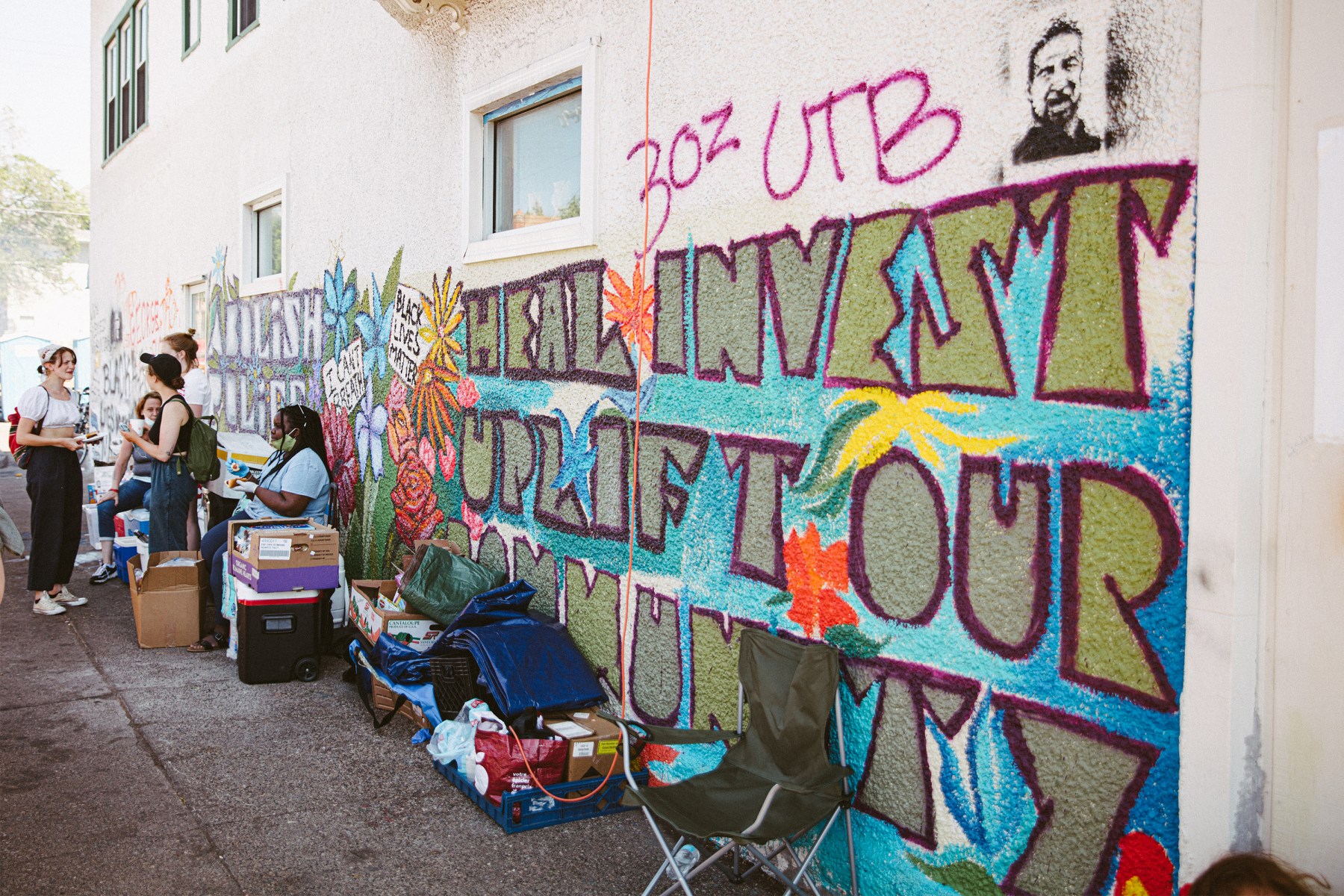 Messages on murals range from "Heal Invest Uplift Our Community" to "Abolish Police."