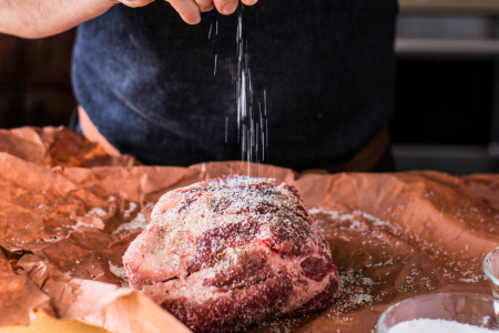 Pork shoulder being seasoned. 