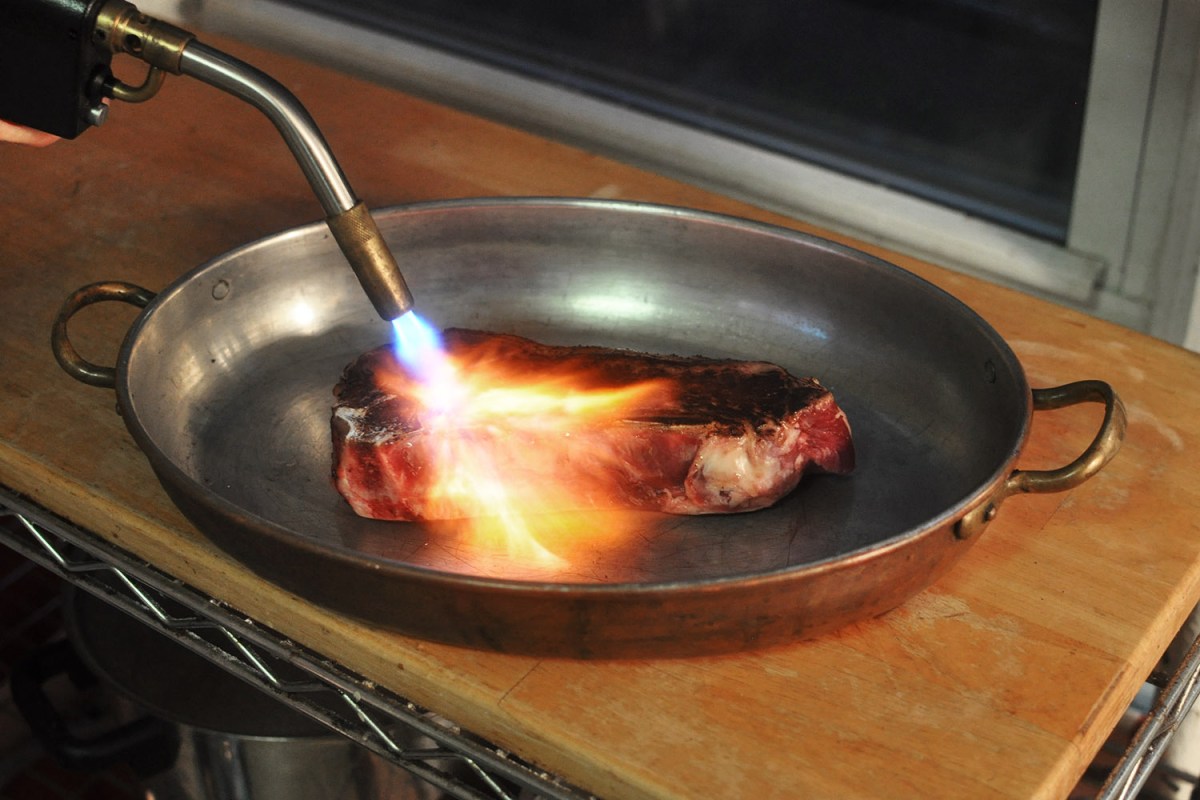A steak is cooked with a blowtorch