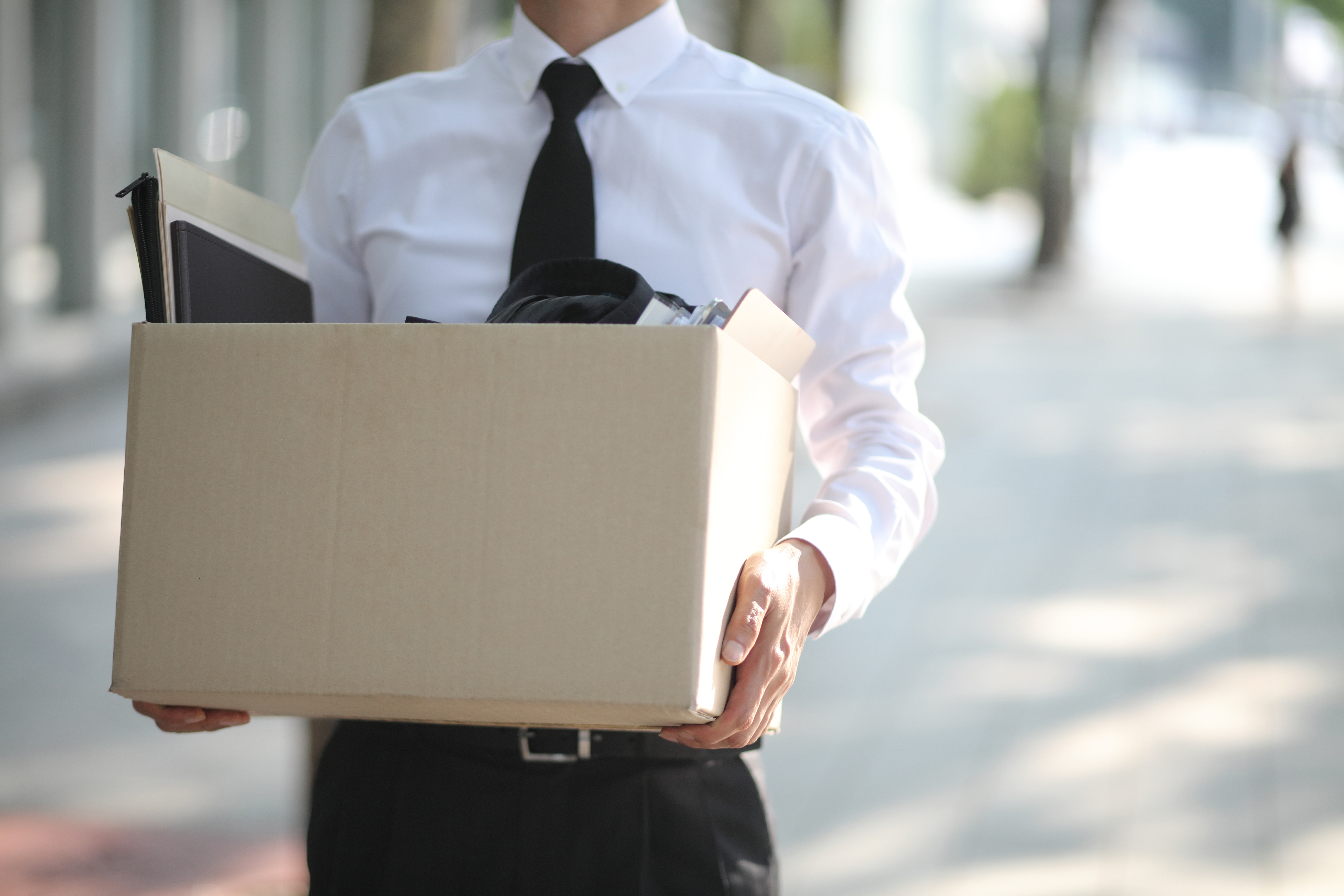 Person in a shirt and tie carrying a box
