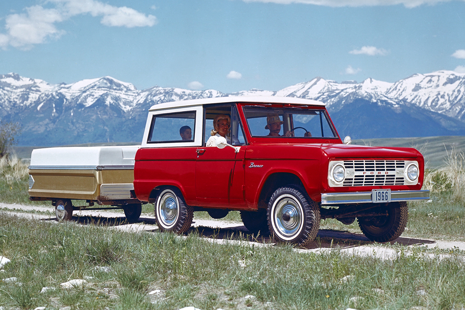 1966 red and white Ford Bronco towing a camper