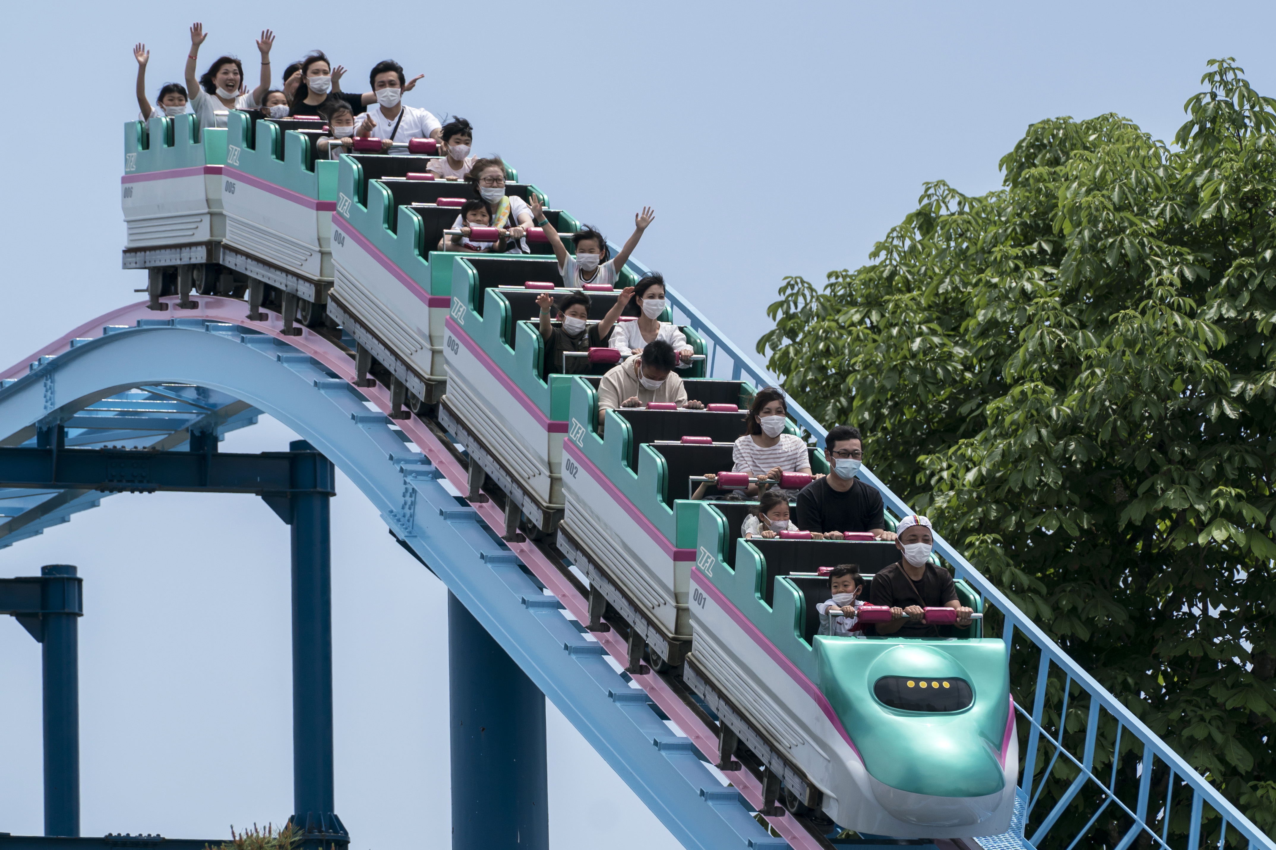 Visitors wearing face masks ride a roller coaster at the Tochinoki Family Land amusement park on May 17, 2020 in Utsunomiya, Tochigi, Japan