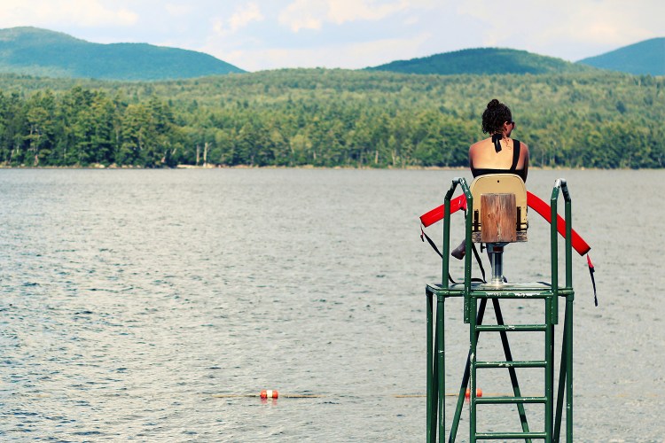 lifeguard sitting on a stand overlooking a lake