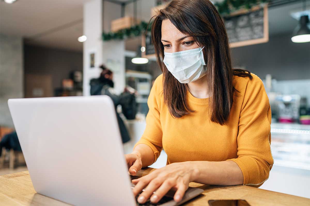 woman wearing a mask using a laptop computer
