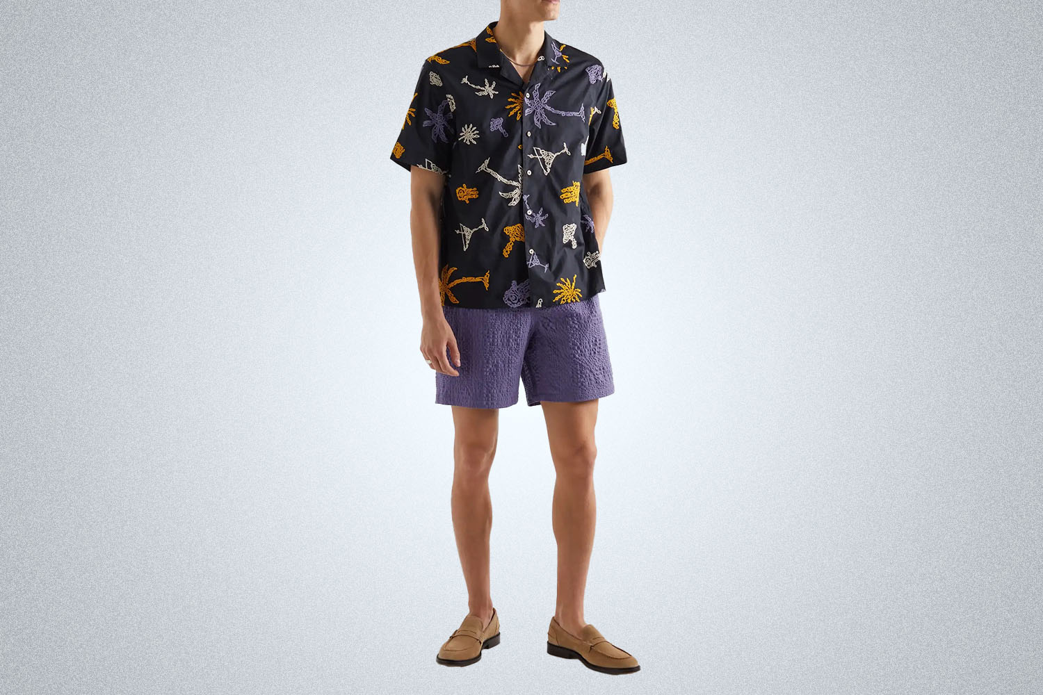 a model in a pair of A Kind of Guise purple shorts on a grey background