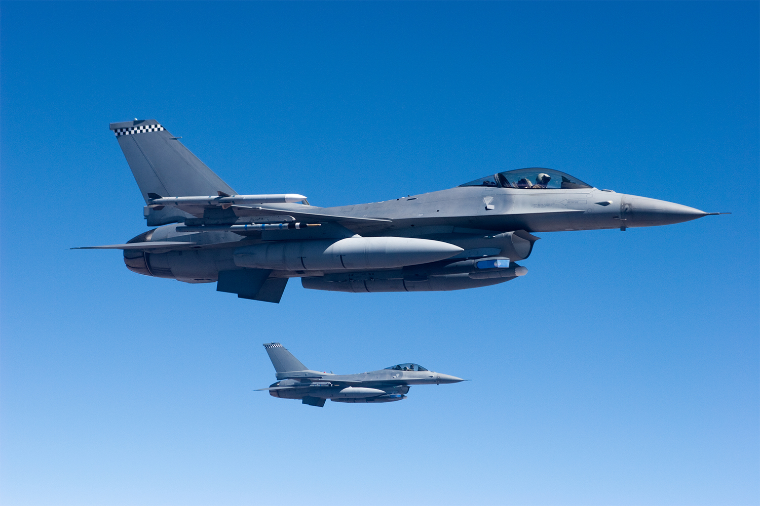 Two F-16 fighter aircraft flying in formation.
