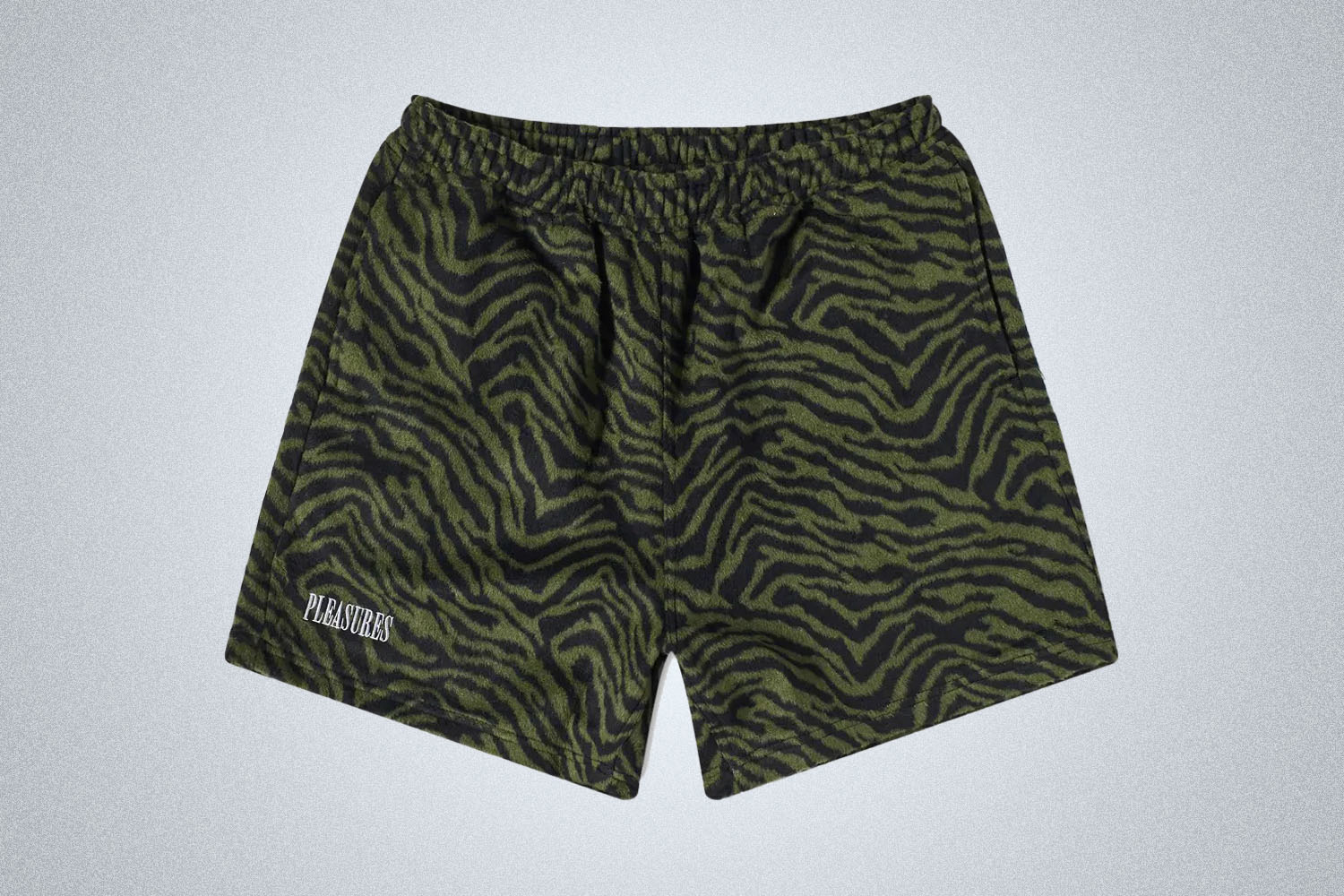 a pair of green pleasures shorts on a grey background