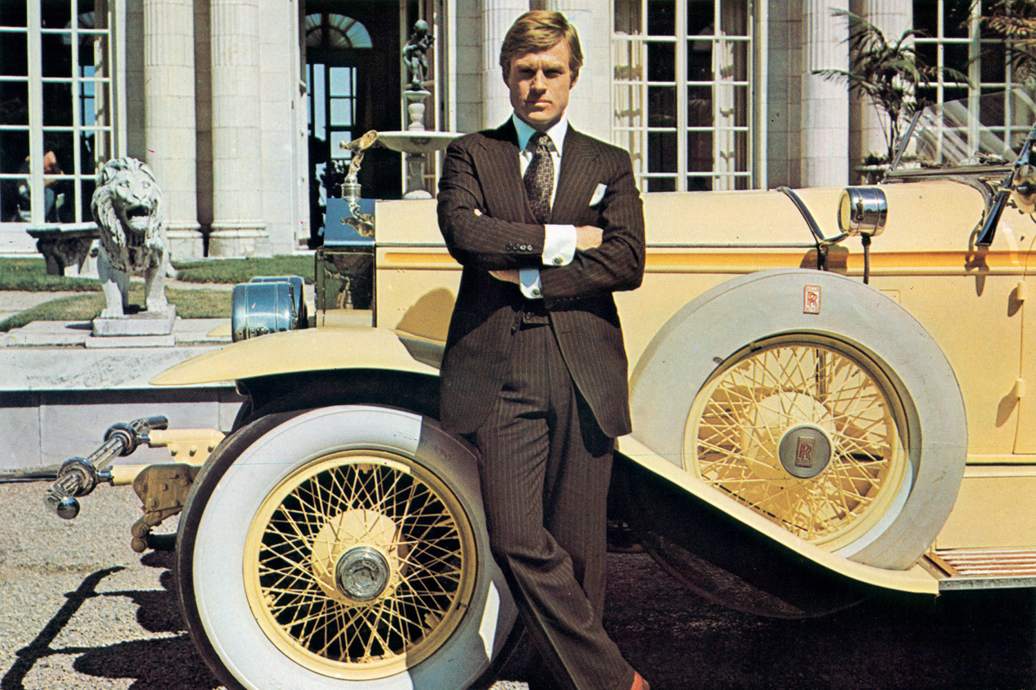 Robert Redford as Jay Gatsby in the 1974 movie adaptation of "The Great Gatsby" stands next to a yellow Rolls-Royce