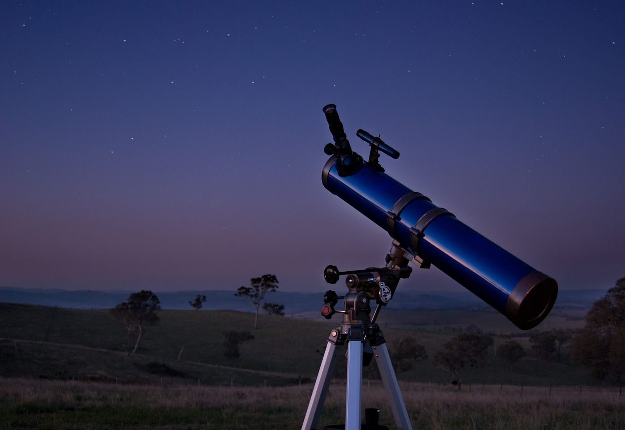 Telescope sitting in a field at dusk