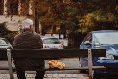 elderly man sitting by himself on a bench