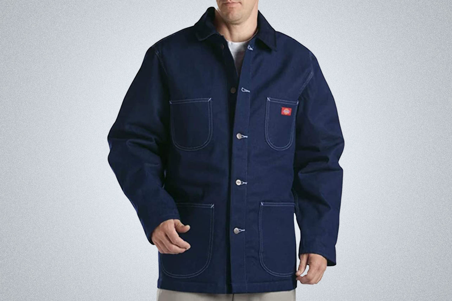 a model wearing a blue Dickies jacket on a grey background