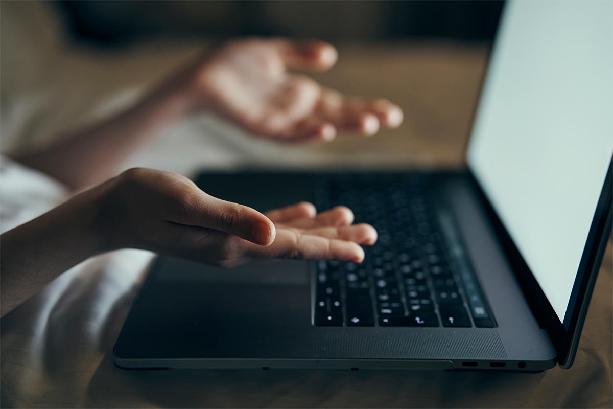 a person holding their hands up over a laptop computer