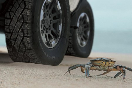 GMC electric Hummer EV SUV using the off-road Crab Mode next to an actual crab
