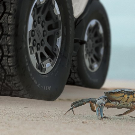 GMC electric Hummer EV SUV using the off-road Crab Mode next to an actual crab