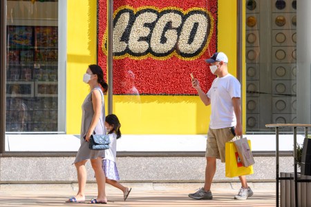 People in masks walk by a Lego storefront