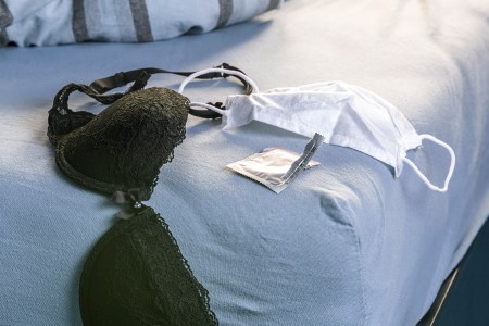a bra, face mask and condom wrapper lying on a bed