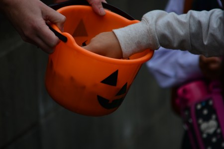 kids trick-or-treating with an orange pumpkin bucket full of candy