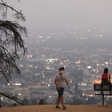 man walking amongst smoke from the wildfires in Los Angeles