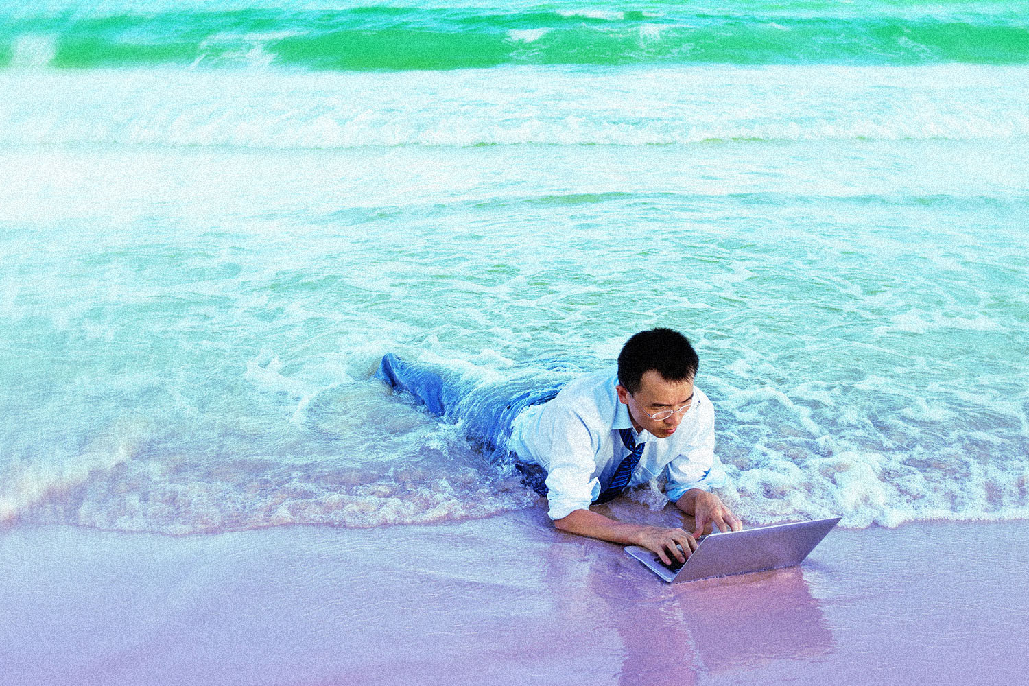 Young businessman on a beach with a laptop.