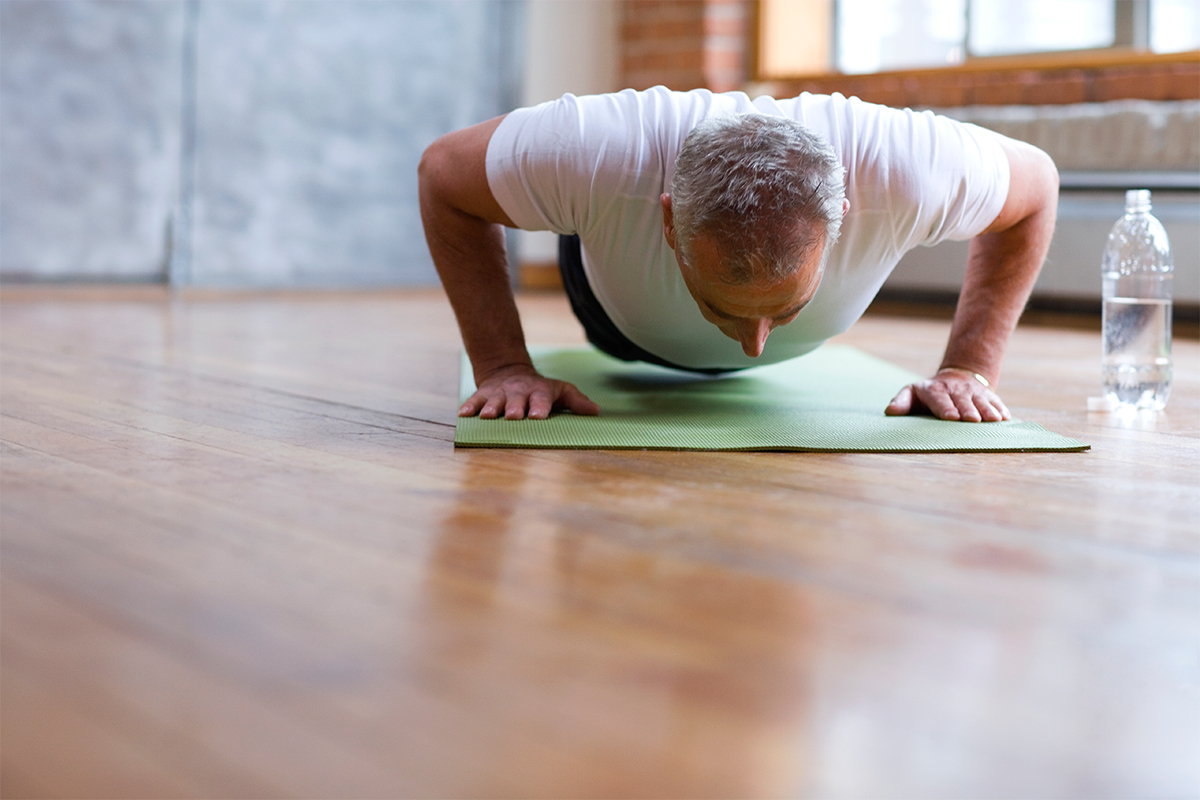 older man doing pushups on a yoga mat