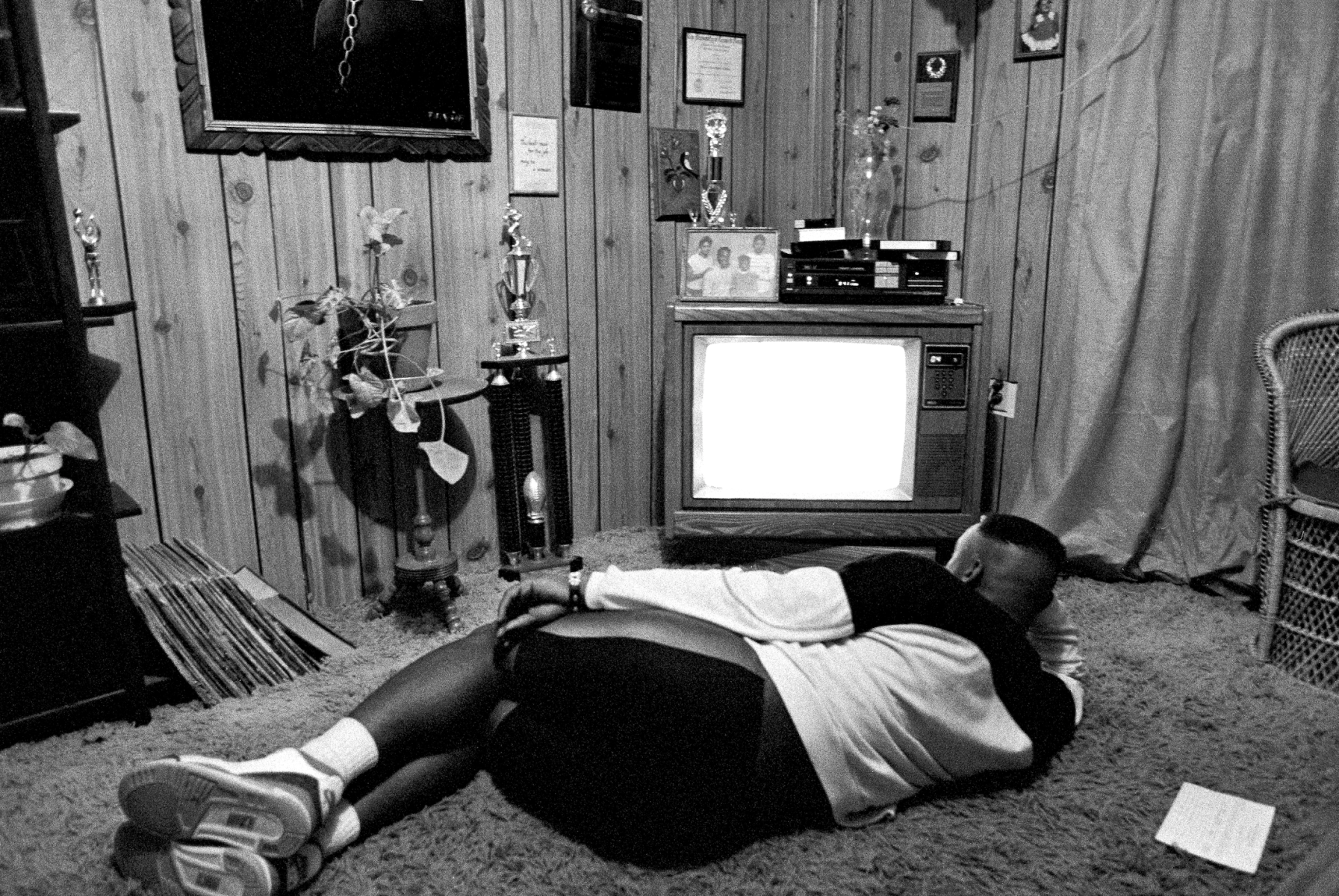 At home, Bobbie Miles watches a VHS highlight reel that his Uncle L.V. put together to send to an assortment of colleges.<br><br>“Bobbie was the star running back, but his career basically ended on kind of a nothing play in spring football during a scrimmage,” Clark says. “This is after he got hurt. He was watching a highlight film of himself. It's kind of glory days — thinking about what might've been. In a lot of ways, when he got hurt and his time was over, he hadn't been prepared for anything else in his life. The school passed him and gave him good grades as long he was a good football player. After that, they didn't didn't help him out much. They kind of used him up and spit him out.”