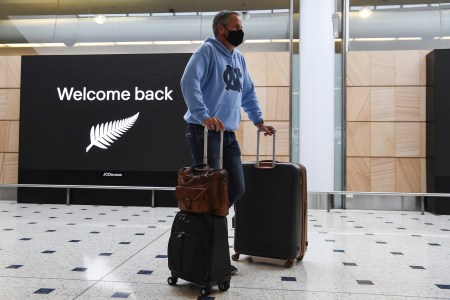 masked man holding suitcases in airport