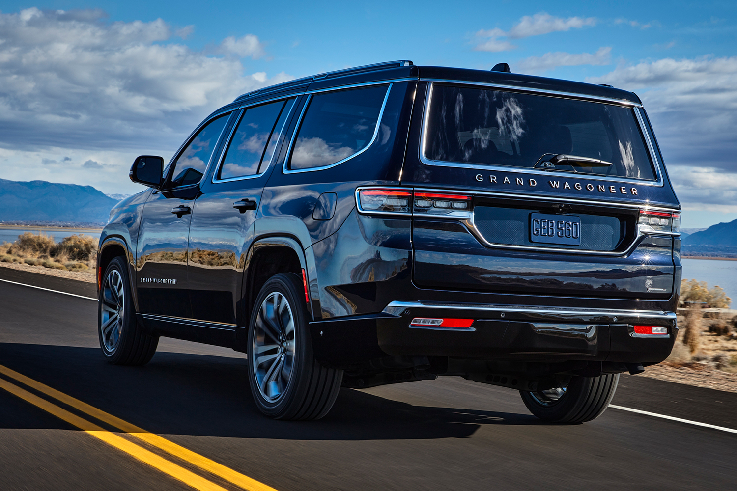 The 2022 Jeep Grand Wagoneer driving down the road shot from the rear left