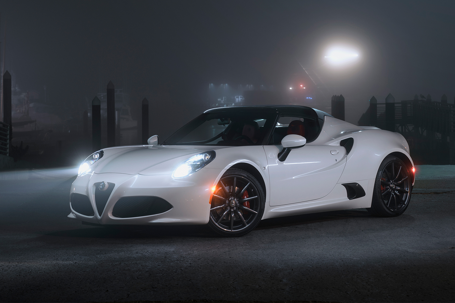 A white Alfa Romeo 4C with its headlights on at night in a foggy area