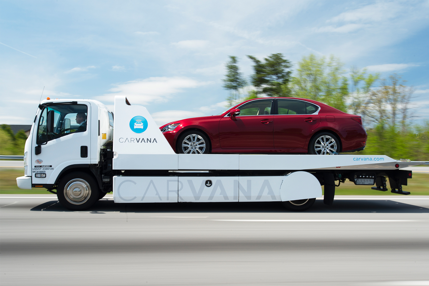 Red car on the back of a Carvana delivery vehicle