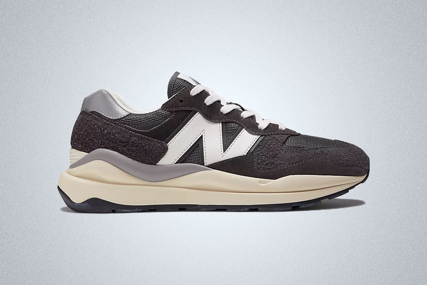 a pair of grey and cream New Balance 57/40 sneaker on a grey background