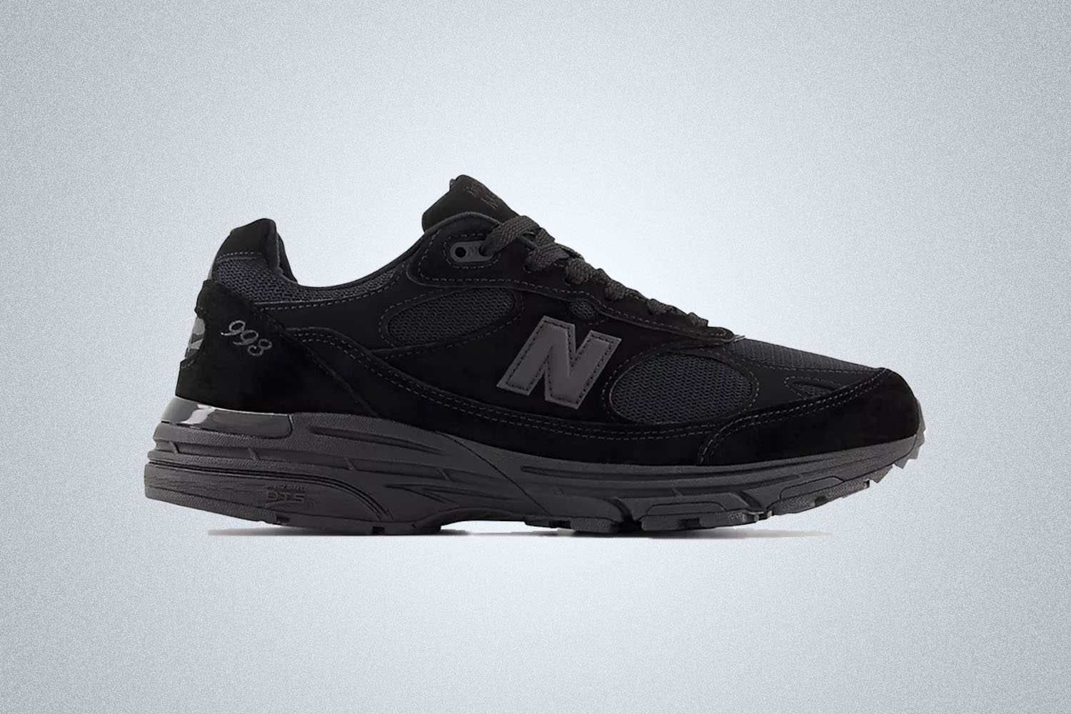 an all black pair of New Balance 993 sneakers on a grey background