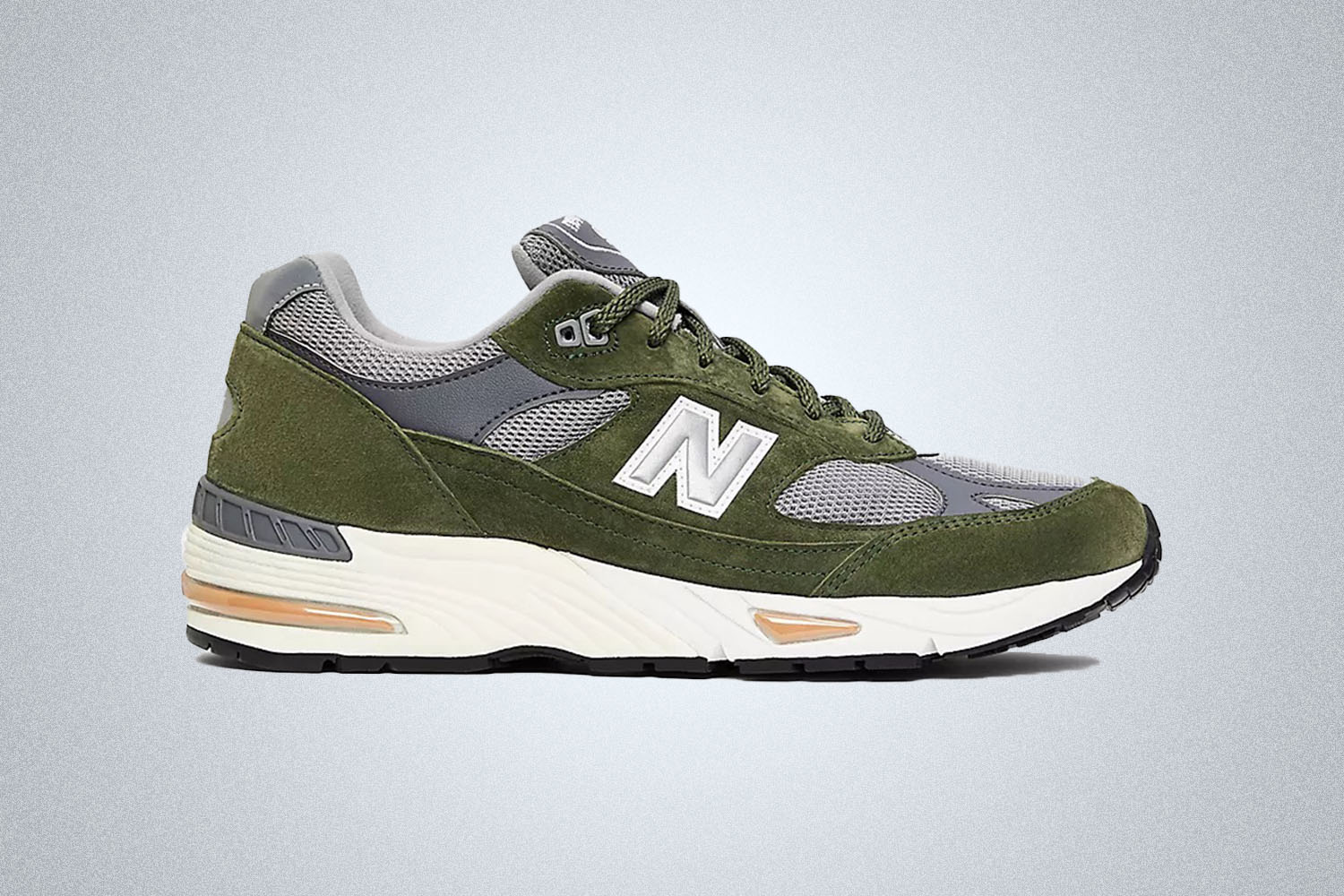 a pair of green New Balance 991 made in the Uk on a grey background