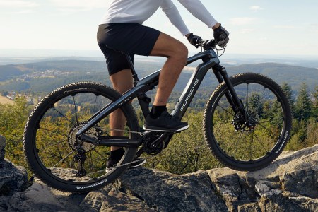 A man on top of a mountain astride the Porsche eBike Cross electric bicycle