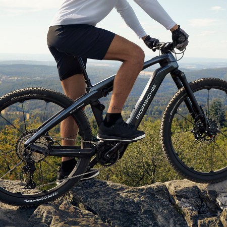 A man on top of a mountain astride the Porsche eBike Cross electric bicycle