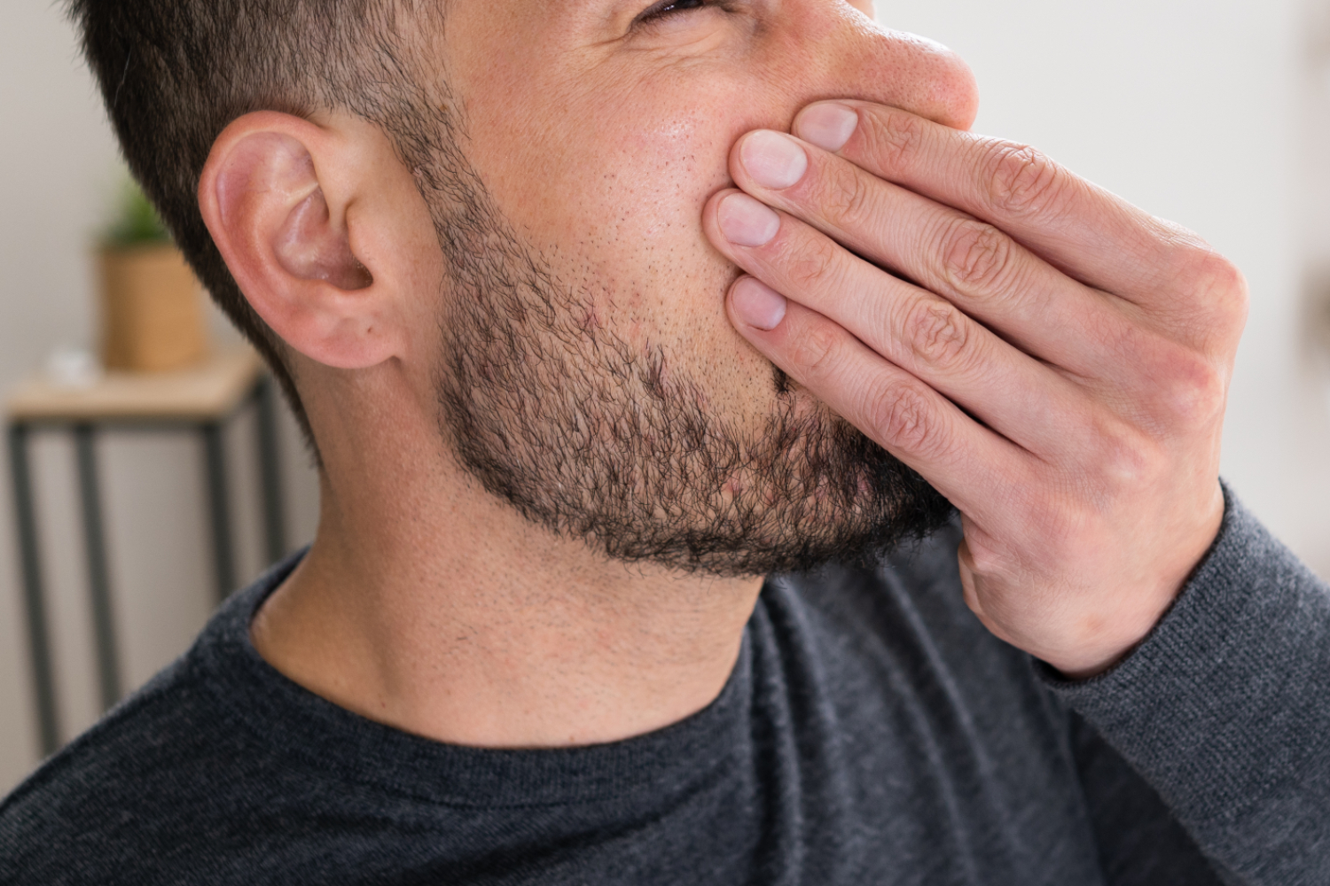 close up of a bearded man holding his nose