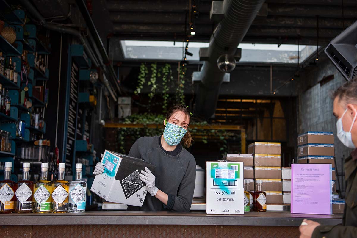 Megan Kyker assists a customer at Cotton & Reed rum distillery in Union Market on Friday, April 3, 2020. Many bars and restaurants are open for takeout orders during the coronavirus outbreak